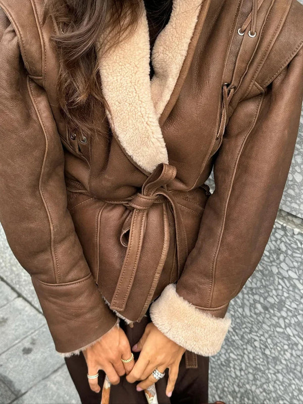 Nahaufnahme einer braunen Lederjacke mit Gürtel an einem Modell